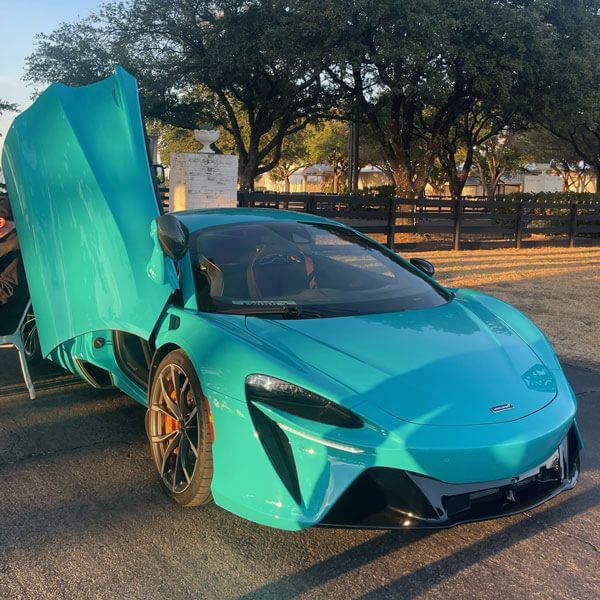 Blue McLaren with doors open, featuring luxury rentals in Dallas, TX & nearby areas